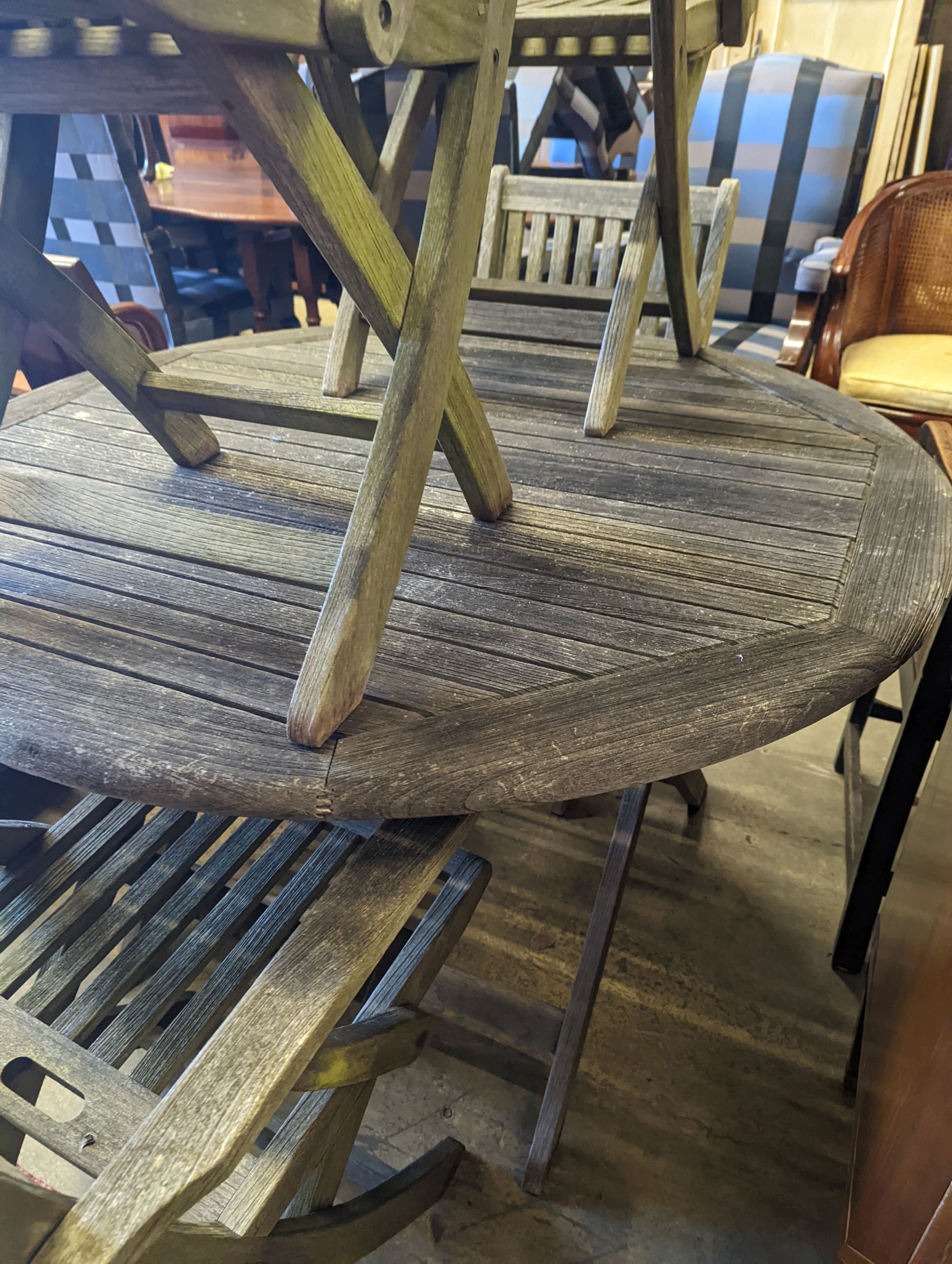 A set of four Westminster teak folding elbow chairs and a weathered teak circular garden table, diameter 120cm, height 73cm